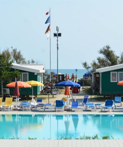 Pool with colorful sunbeds and umbrellas near the sea.