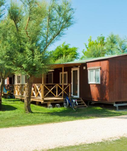 Wooden bungalow with a veranda in a green campsite.