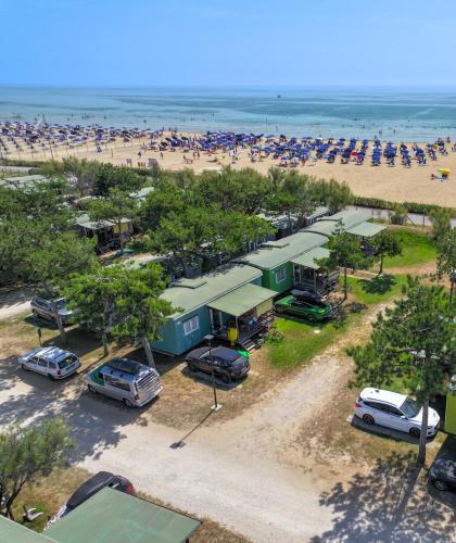 Strand mit Sonnenschirmen, Mobilheimen und geparkten Autos am Meer.