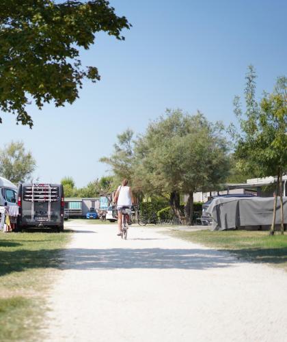 Campeggio con camper, biciclette e una persona che pedala.