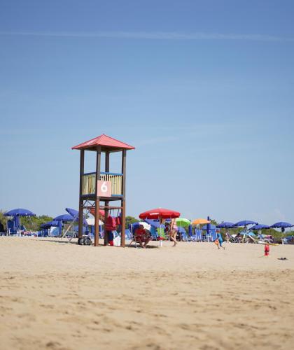 Sandstrand med livreddertårn og farverige parasoller.