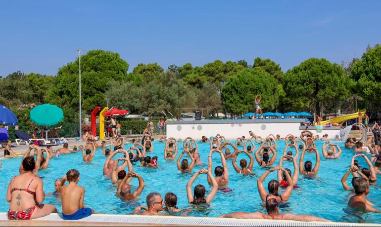 Aquagym-klasse i udendørs pool med mange deltagere.